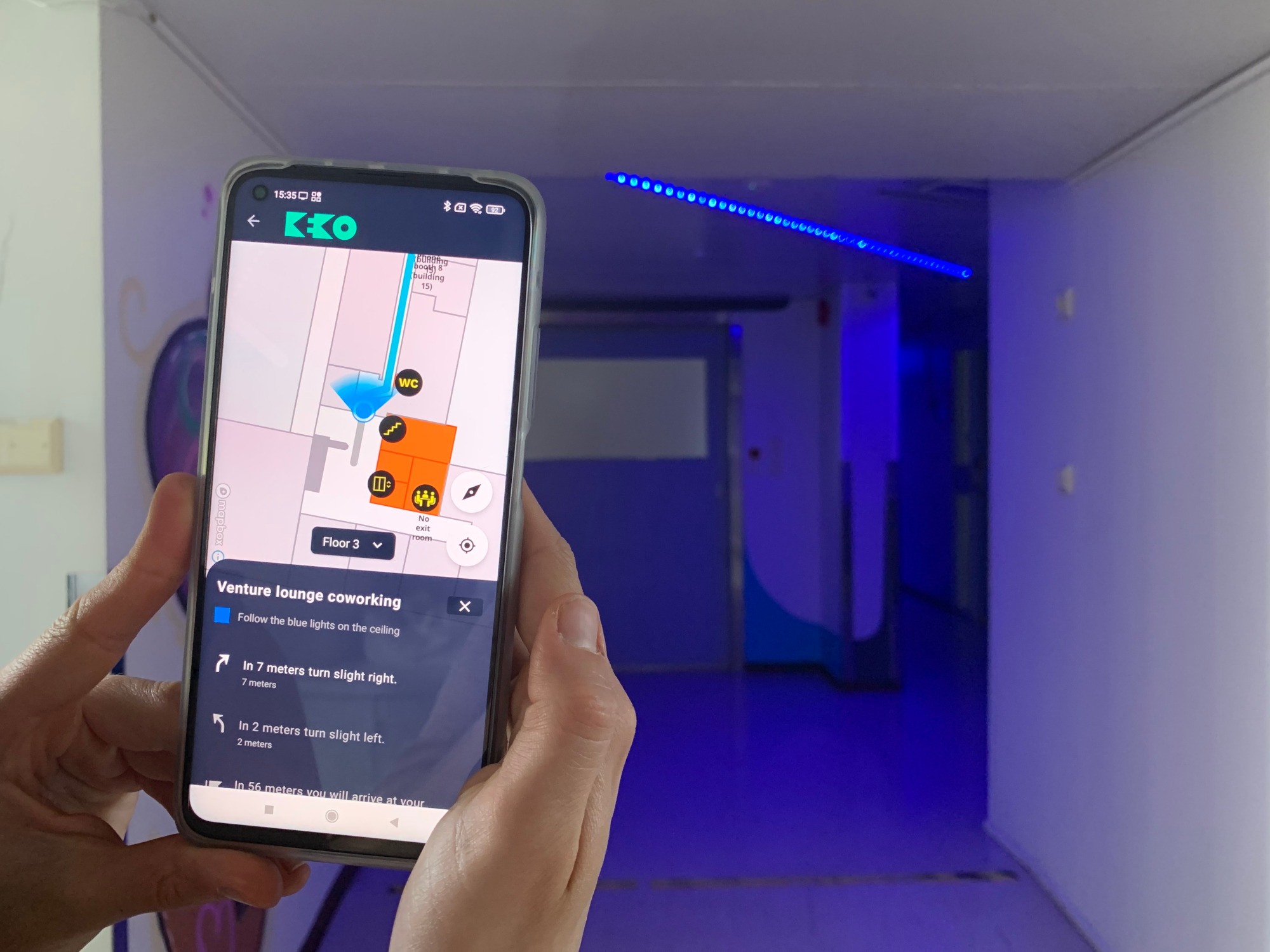 Closeup of a mobile phone showing indoor navigation application. Blue lights in the background.